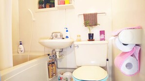 A bathroom with a bathtub, sink, toilet, and a shelf with toiletries. - suzuki4 (Tokyo)