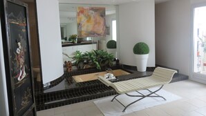 Un baño moderno con una bañera, una silla blanca y un espejo grande.
