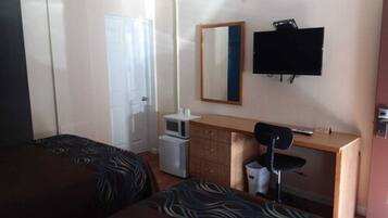 A hotel room with two beds, a desk, a chair, a television, and a small refrigerator.