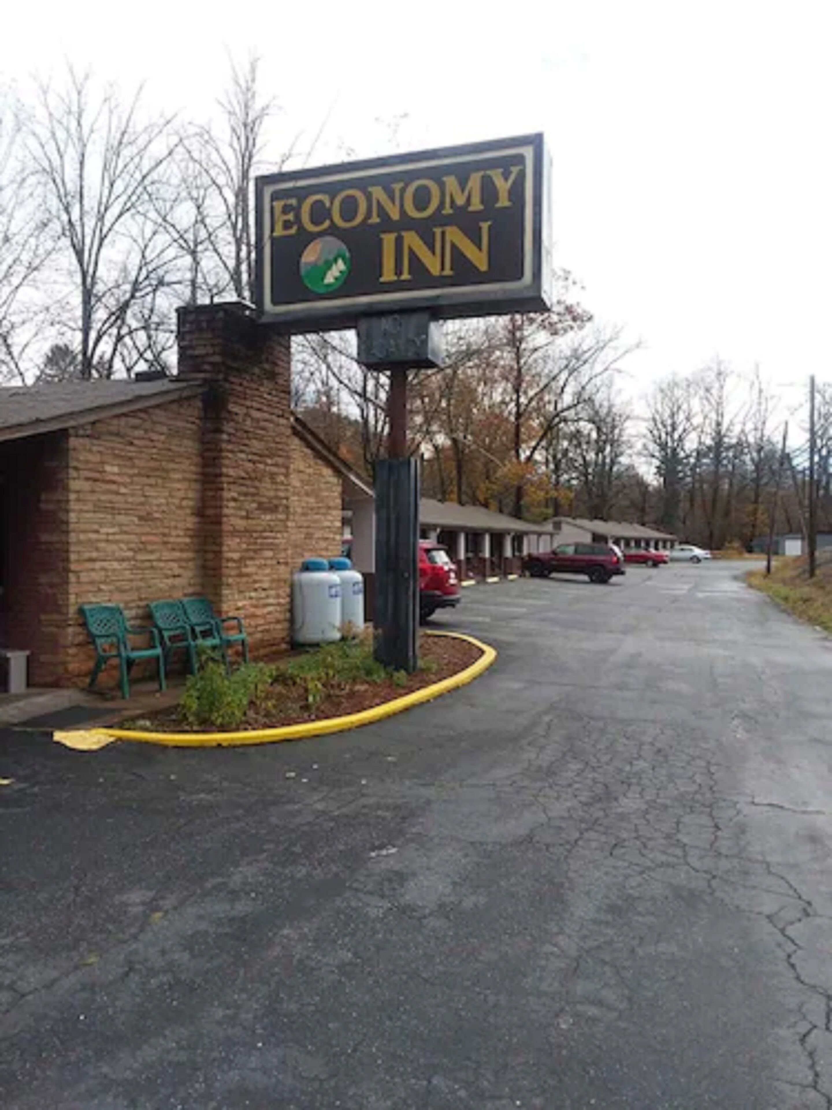 A sign for Economy Inn with a brick building and a parking lot.