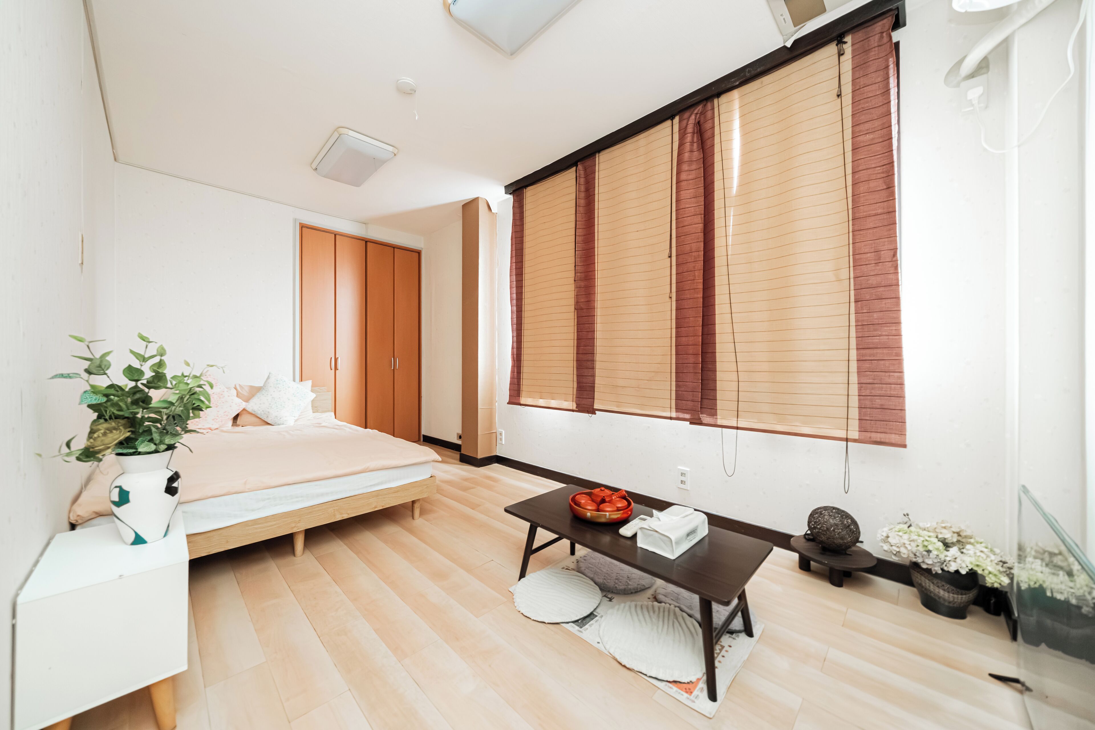 A modern bedroom with a bed, bedside table, and a window with blinds.