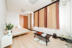 A modern bedroom with a bed, bedside table, and a window with blinds. - suzuki6 (Tokyo)