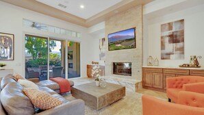 A spacious living room with a fireplace, a large window, and a view of the outdoors.