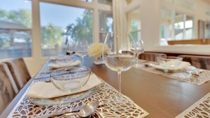A dining table set with clear glassware and plates, surrounded by a white lace table runner.