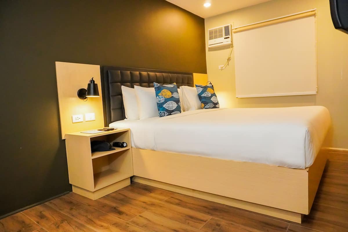 A neatly arranged bedroom with a bed, bedside tables, and a wall-mounted air conditioner.