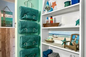 Enjoy a beachside retreat with a nautical theme, featuring a wall-mounted towel rack and a shelf with personal touches.