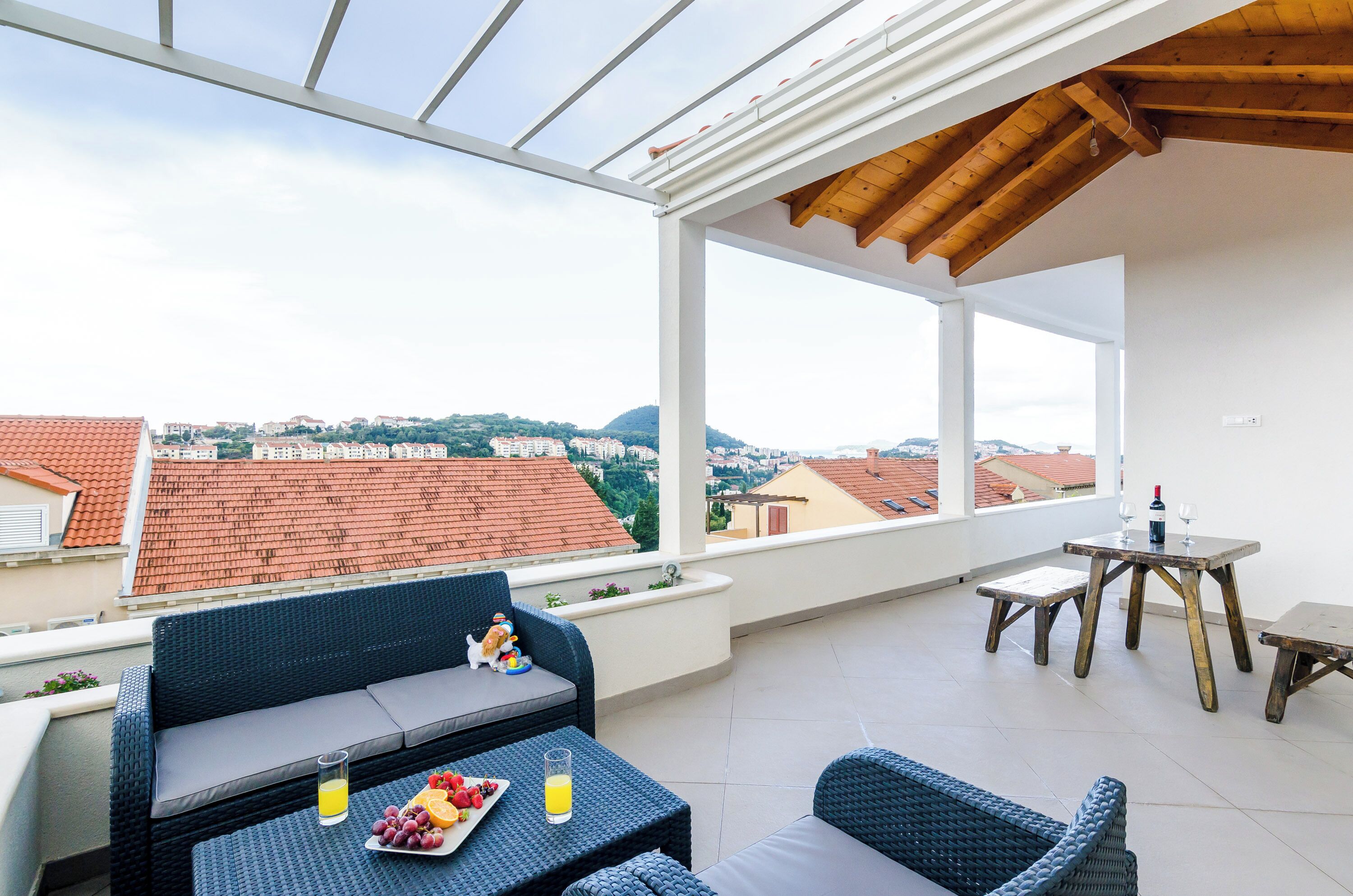 Une terrasse sur le toit, meublée de mobilier en osier, avec une table où sont disposées des boissons, et d’où l’on peut admirer le panorama de la ville.