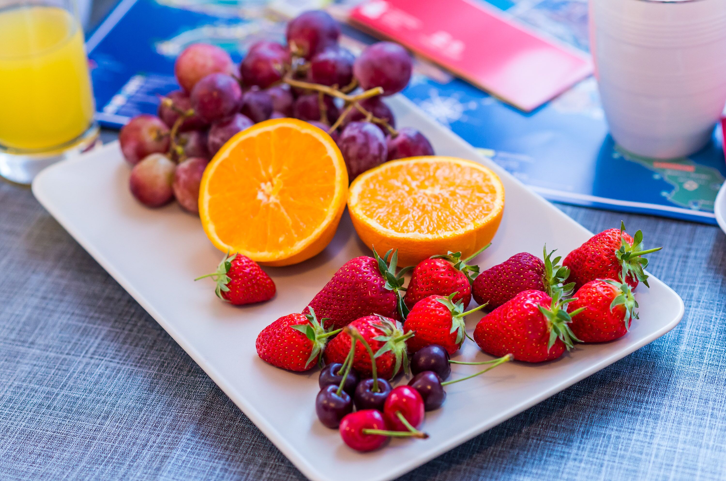 A plate of fresh fruits including strawberries, grapes, and oranges.