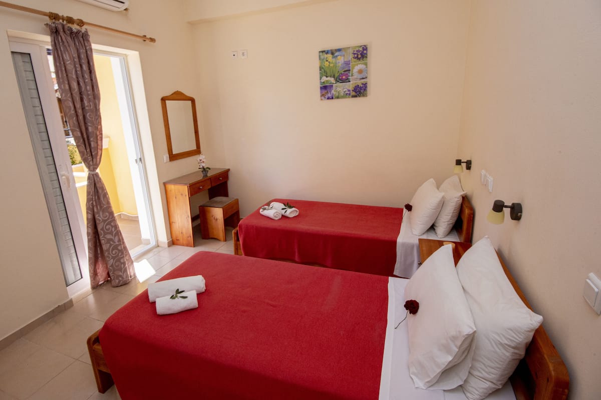 A hotel room with two single beds, a wooden dresser, a mirror, and a painting on the wall.