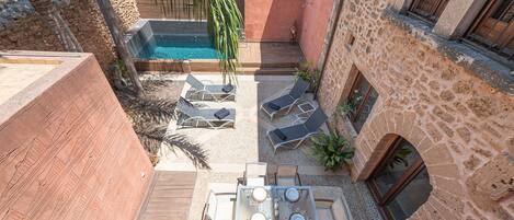 A rooftop terrace with a pool, lounge chairs, and a dining area.