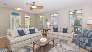 A living room with two beige sofas, a wooden coffee table, and a striped armchair. - Spacious Coastal Home w/ Close Beach Access & Private Pool in Destin! 🌊🌴☀ (Destin)
