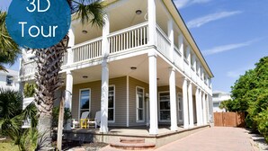 A two-story house with a covered porch, white columns, and a fenced yard. - Spacious Coastal Home w/ Close Beach Access & Private Pool in Destin! 🌊🌴☀ (Destin)