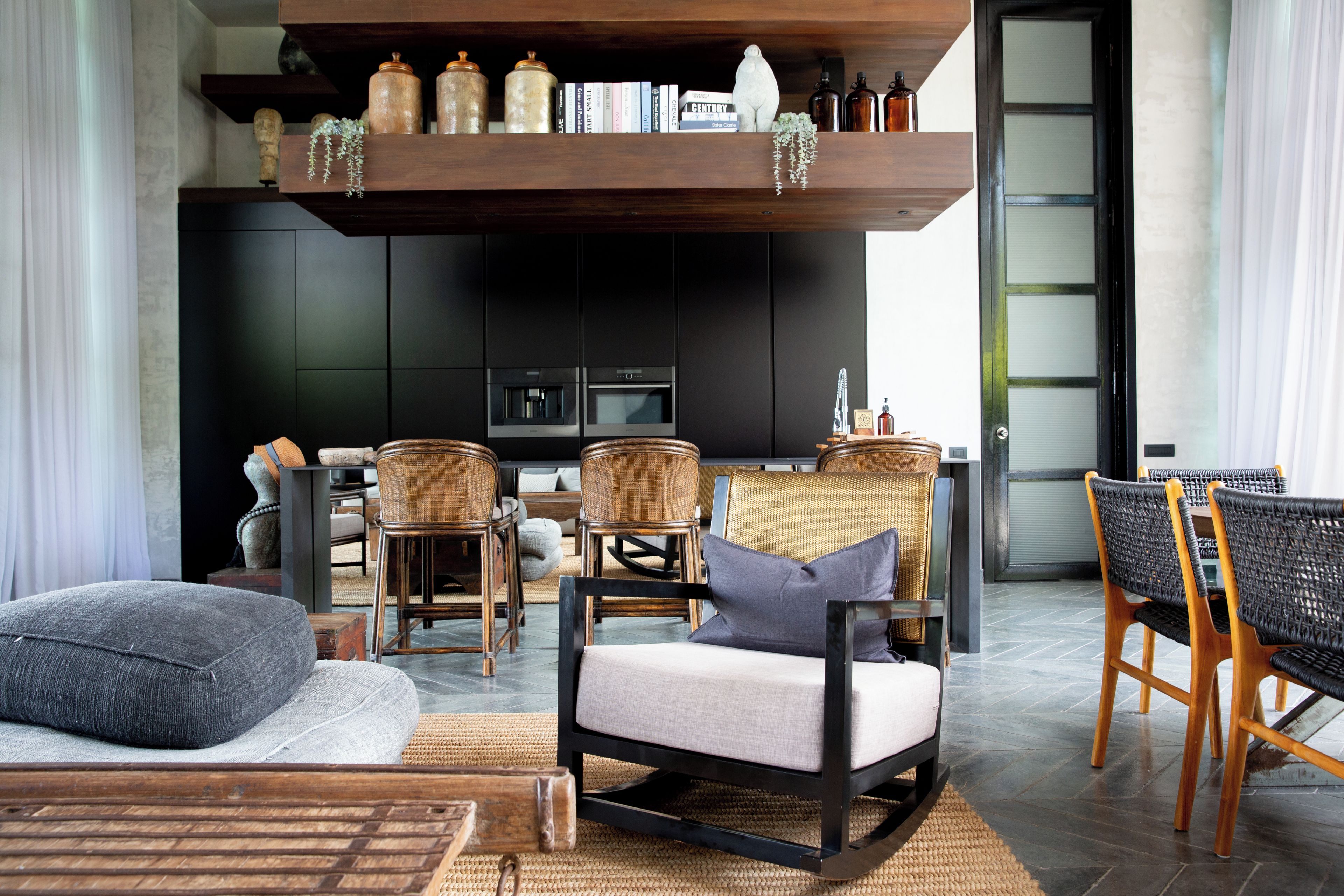 A modern living room with a sofa, chairs, a coffee table, and a bookshelf with books and decorative items.