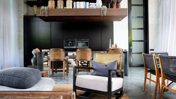 A modern living room with a sofa, chairs, a coffee table, and a bookshelf with books and decorative items.