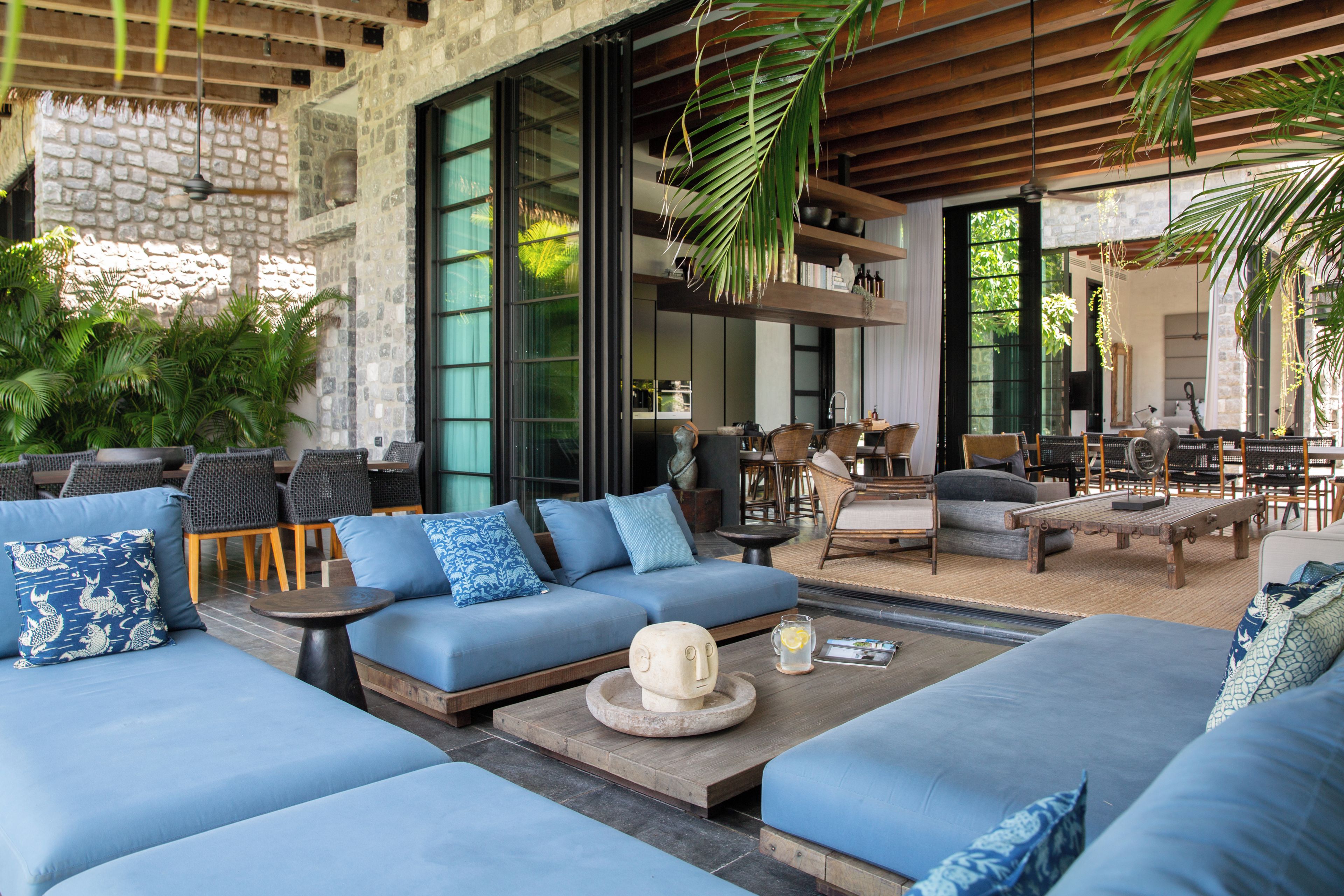 A modern outdoor seating area with sofas and chairs, a coffee table, and a stone wall.