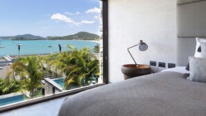 A bedroom with a large window overlooking a pool and a view of the sea. - Clay Beach Samui (Koh Samui)