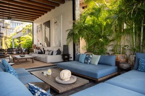 A modern living room with a blue sofa, wooden coffee table, and a stone sculpture. - Clay Beach Samui (Koh Samui)