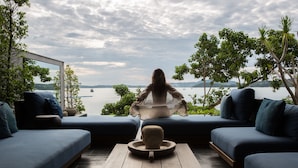 A serene outdoor seating area with a view of a lake and distant hills. - Clay Beach Samui (Koh Samui)