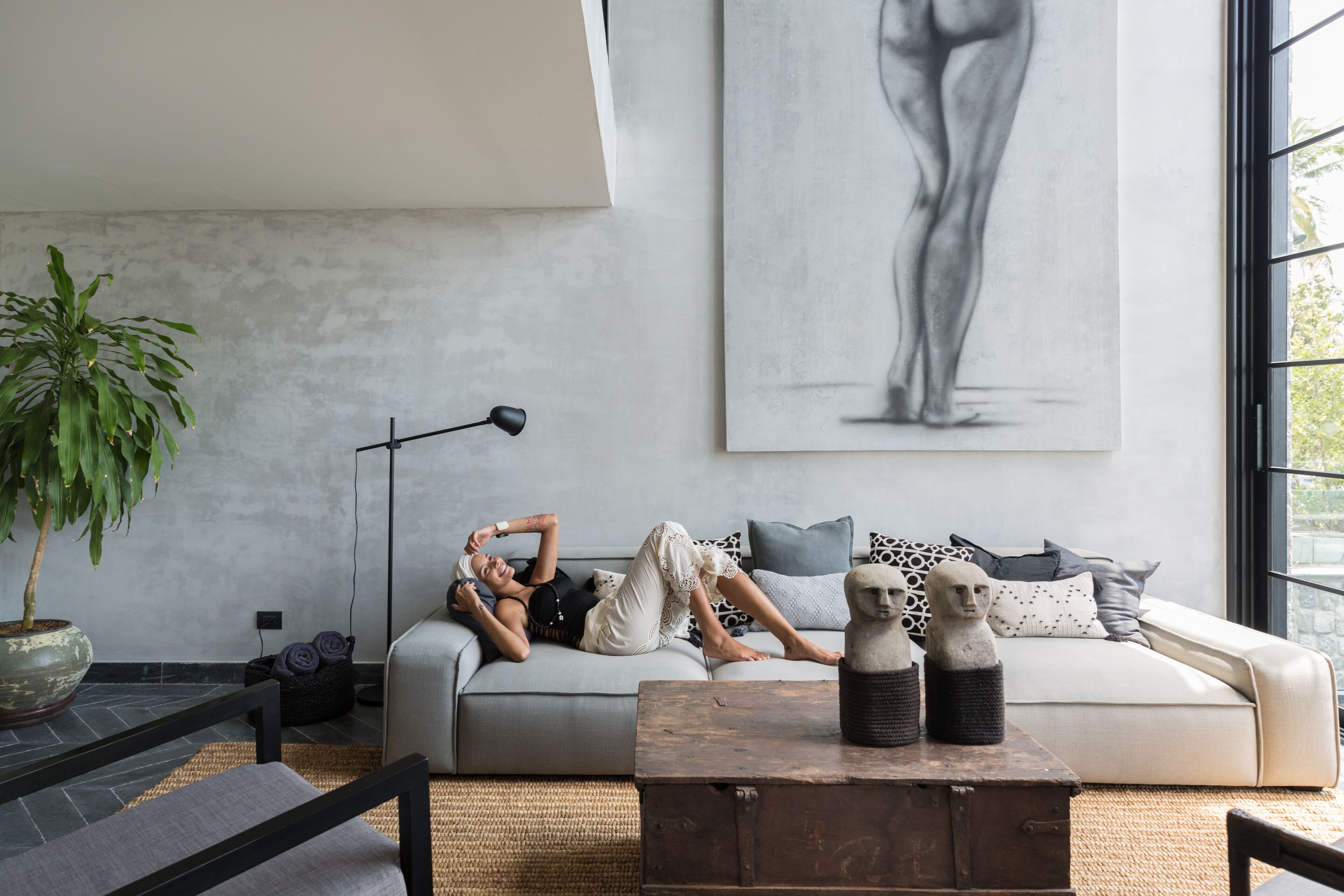 A modern living room with a sofa, a coffee table, a floor lamp, and a large window.