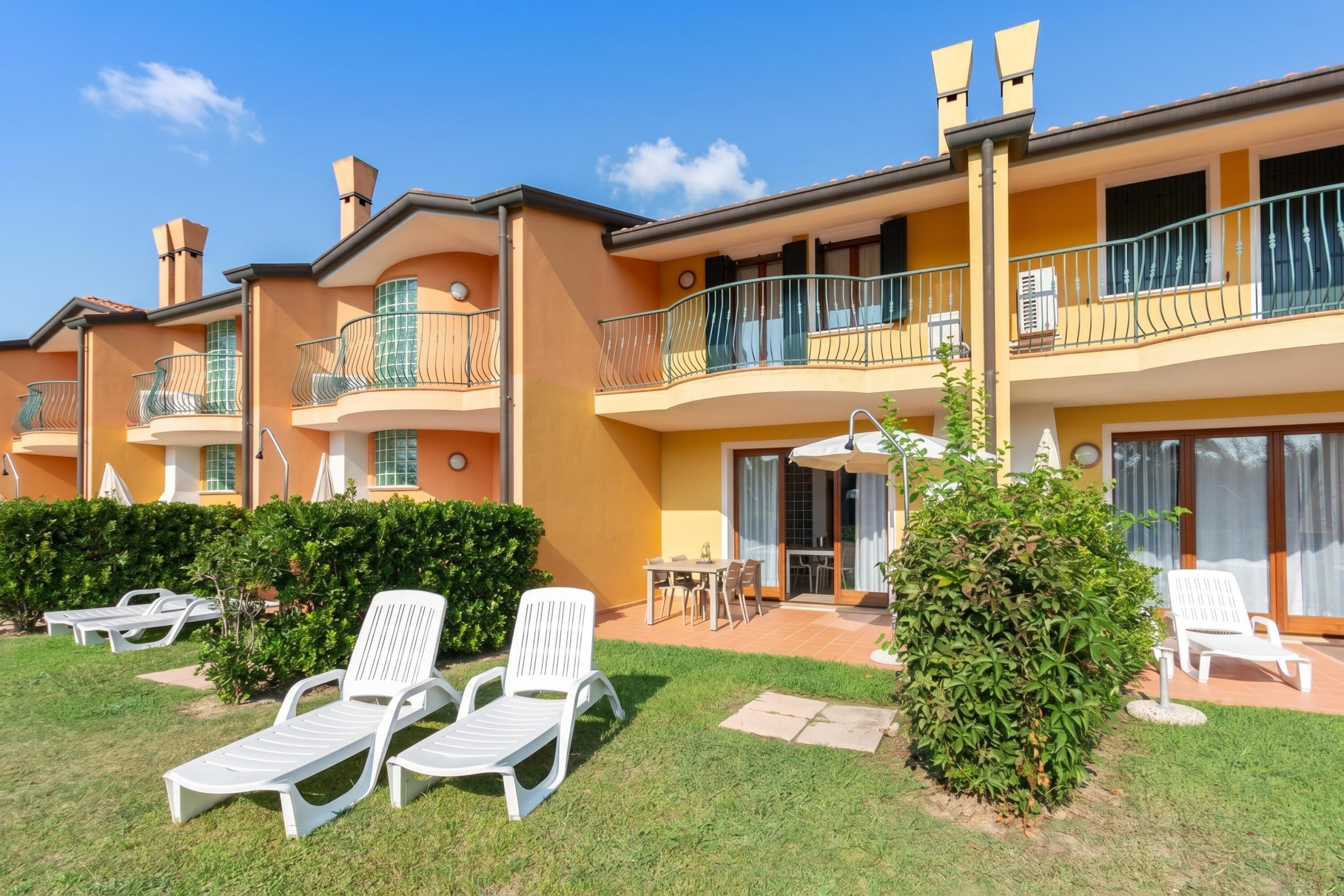 A multi-story hotel with balconies, outdoor seating, and a well-maintained lawn.