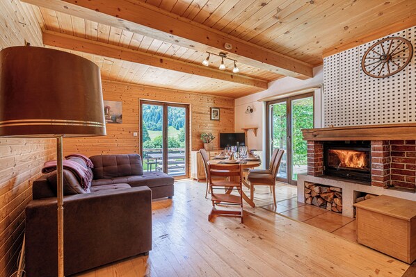 Ein gemütliches Blockhaushaus-Interieur mit Kamin, Holzmöbeln und einem Essbereich.