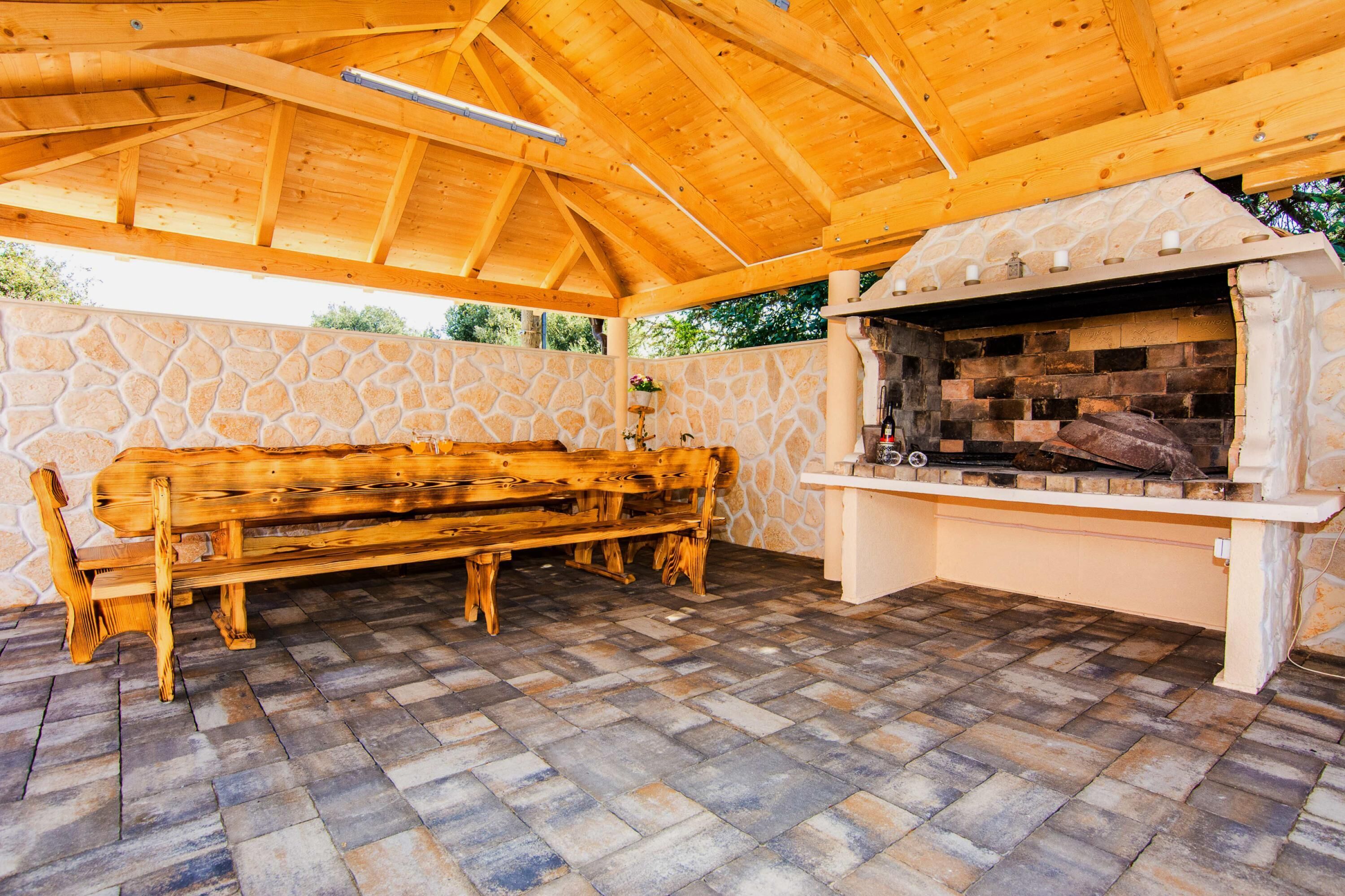 Eine Terrasse im Freien mit einer Steinwand, einer Holzbank und einem Steinkamin.