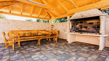 Eine Terrasse im Freien mit einer Steinwand, einer Holzbank und einem Steinkamin.