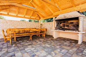 Un patio al aire libre con una pared de piedra, un banco de madera y una chimenea de piedra.