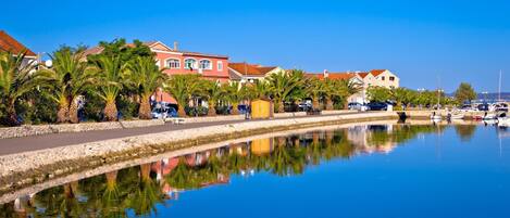 A waterfront property with a canal, palm trees, and buildings with red roofs.