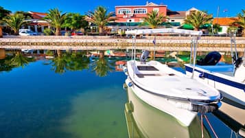 Un puerto deportivo con barcos amarrados, agua cristalina y edificios al fondo.