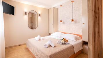 A hotel room with a large bed, a flat-screen TV mounted on the wall, and a mirror.
