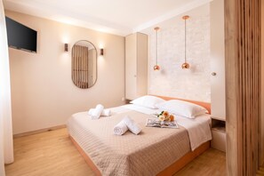 Habitación de hotel con una cama grande, un televisor de pantalla plana montado en la pared y un espejo.