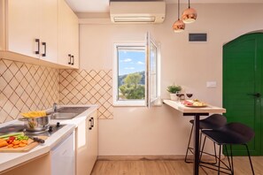 A kitchen with a window, a green door, and a dining area with chairs. - Pool Villa Vese /w Panoramic Sea View (Marina)