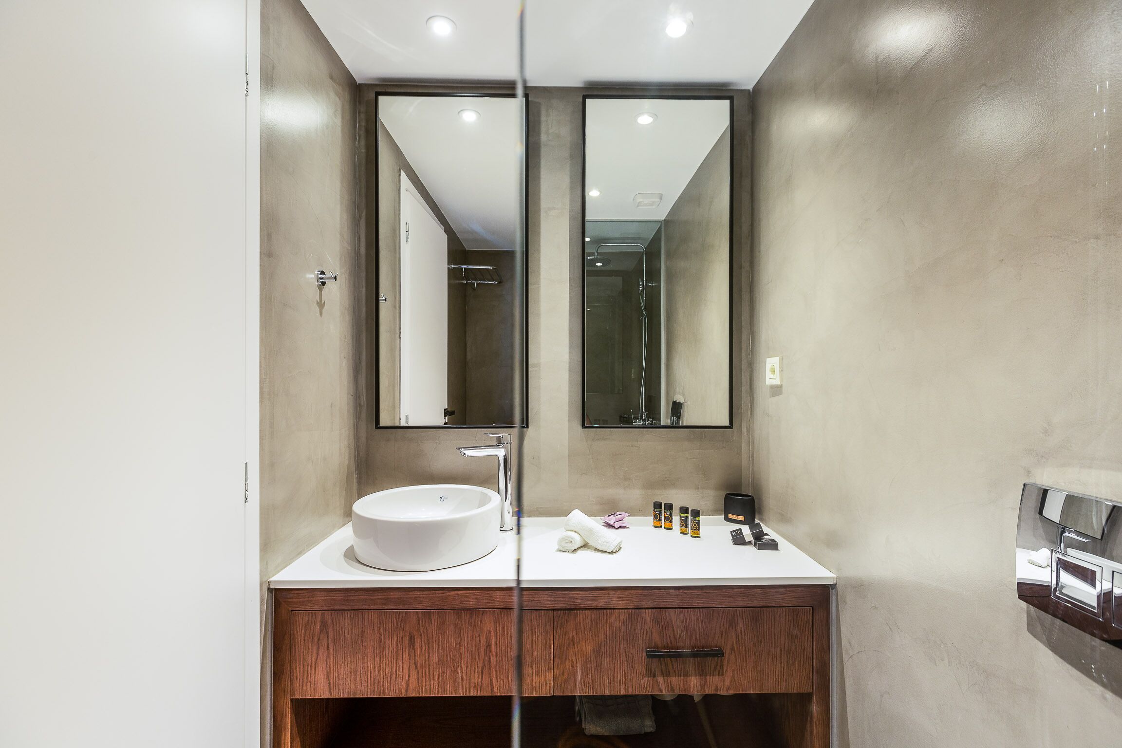 Un baño moderno con un espejo grande, un lavamanos blanco y un mueble de tocador de madera.