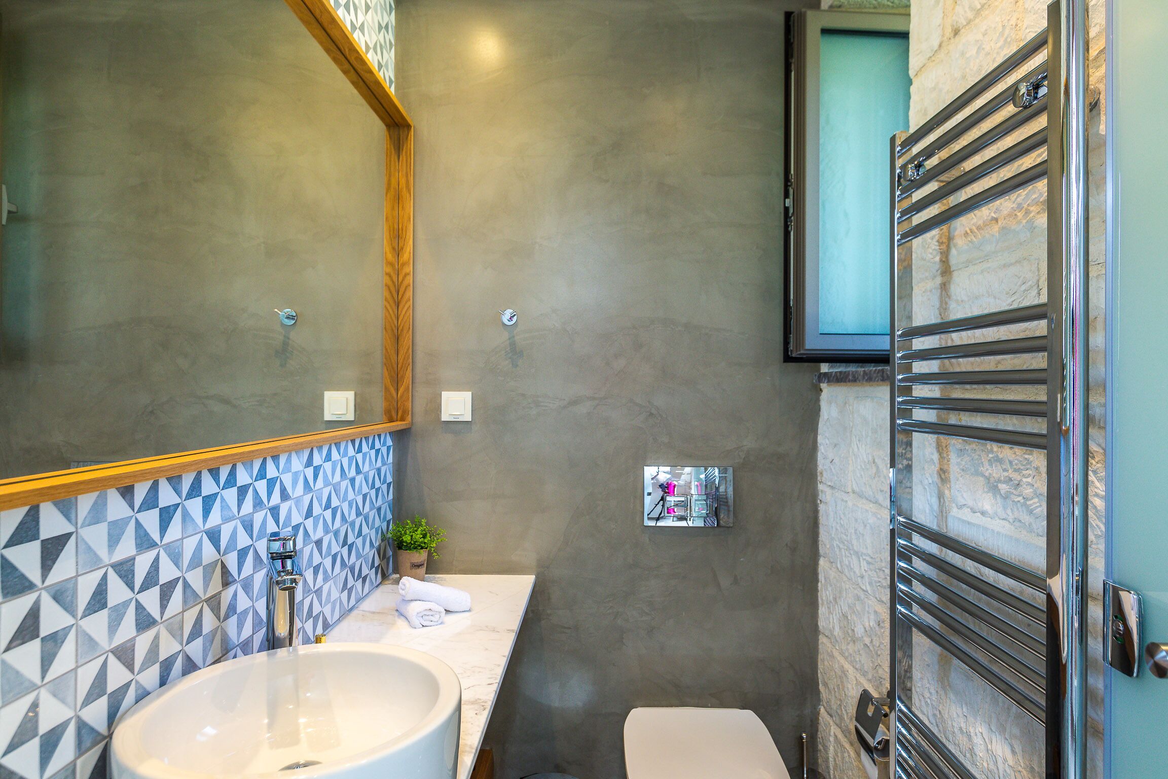 A bathroom with a large mirror, a sink, a toilet, and a towel rack.