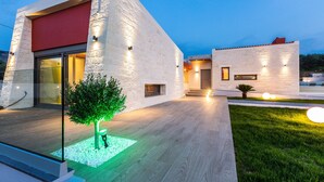 A modern building with a large glass entrance, a red awning, and a well-lit exterior. - Villa Aori (Apokoronas)