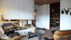 Una sala de estar moderna con un sofá, sillones, una mesa de centro de vidrio y una chimenea.
