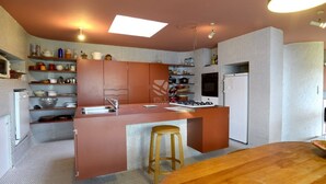 Cocina moderna con una isla central, taburetes de madera y horno empotrado.
