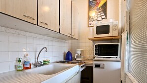 A compact kitchen with white cabinets, a sink, a microwave, and a coffee maker. - Cozy studio at the slopes with balcony, pets welcome (Chamrousse)