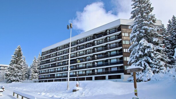 A multi-story building with balconies, surrounded by snow-covered trees and a snow-covered pathway. - Cozy studio at the slopes with balcony, pets welcome (Chamrousse)