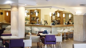 Un espace bar moderne, doté d’un assortiment de bouteilles d’alcool, d’un comptoir et de tabourets de bar.