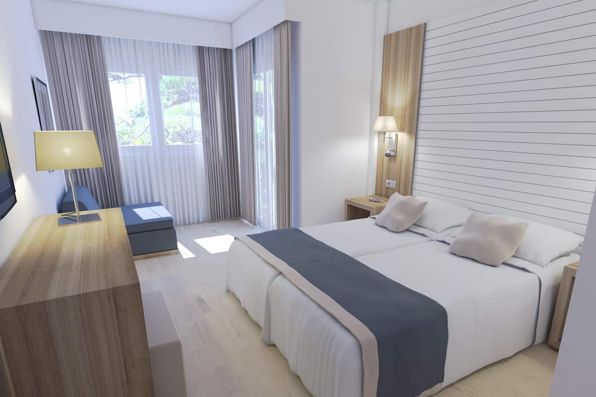A modern hotel room with a large bed, a desk with a lamp, a nightstand, and a window with curtains.