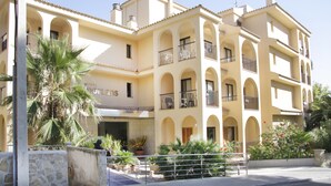 Un hôtel à plusieurs étages, doté d’une façade jaune, de balcons et d’une cour intérieure agrémentée de plantes.