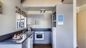 A compact kitchen with a sink, stove, and refrigerator, featuring a fire action notice on the wall. - Turangi Leisure Lodge (Turangi)