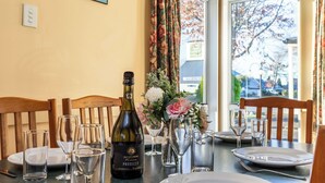 A dining table set with wine glasses, a bottle of wine, and a vase with flowers. - Turangi Leisure Lodge (Turangi)