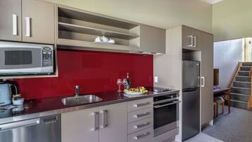 A modern kitchen with stainless steel appliances, a red backsplash, and a built-in oven.