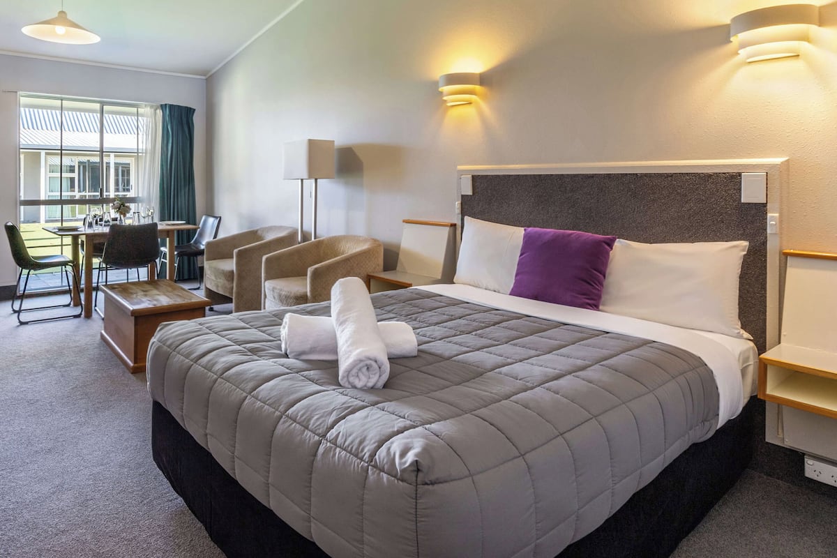 A hotel room with a large bed, a desk, and a chair.