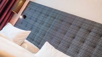 A neatly made bed with white linens and a grey headboard.