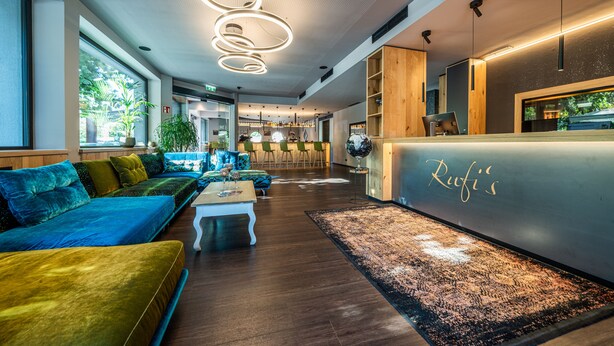 Una hall moderna con divano, reception e area bar.