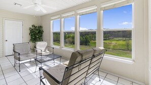 A sunroom with large windows, a ceiling fan, and a view of a golf course. - Walk-in Golf Condo with Course View from All-Season Sunroom (Branson)